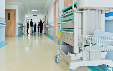 Clean healthcare facility corridor with carts of equipment and people standing in the distance.